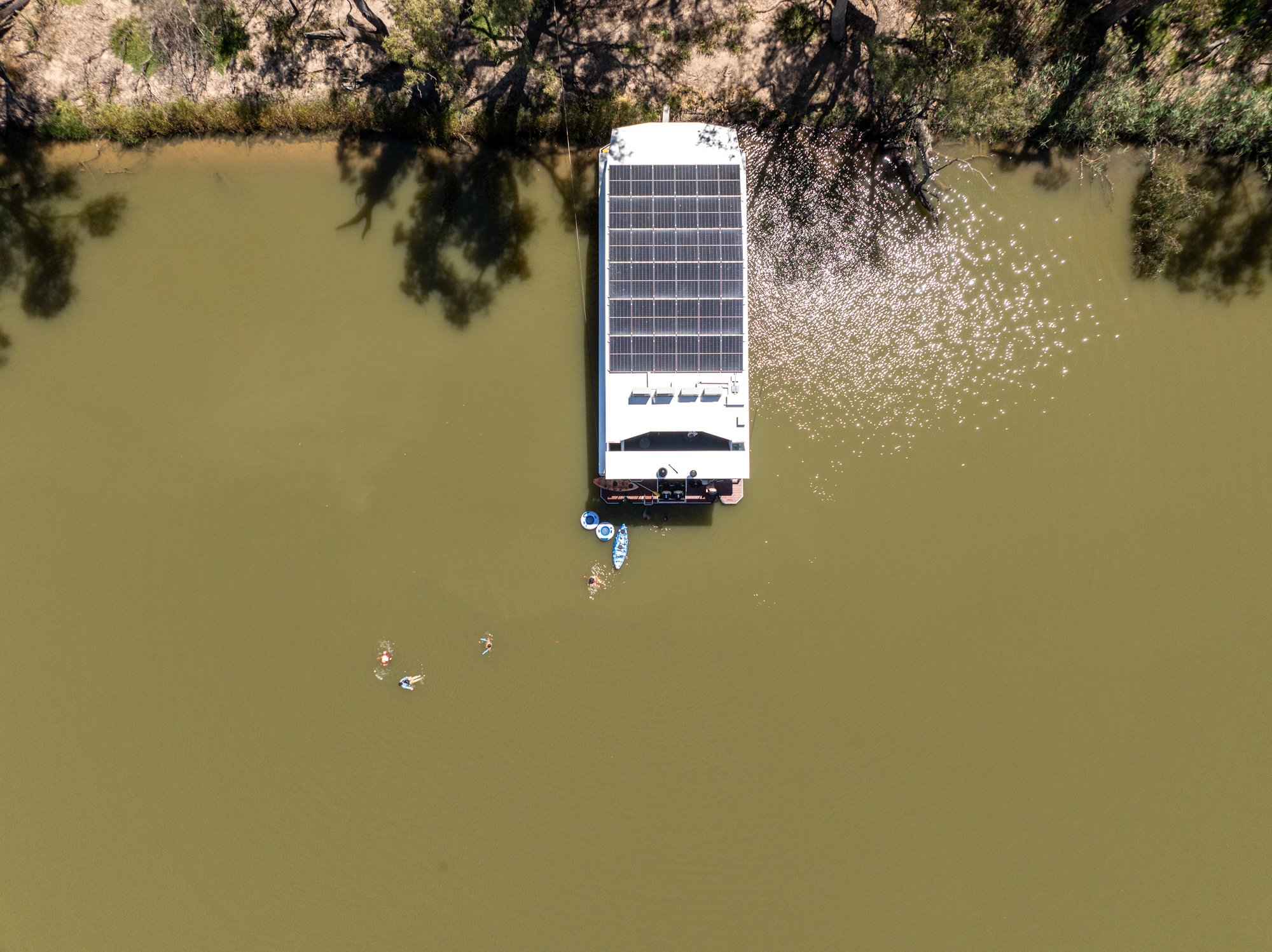 People swimming at the back of a house boat on the Murray River