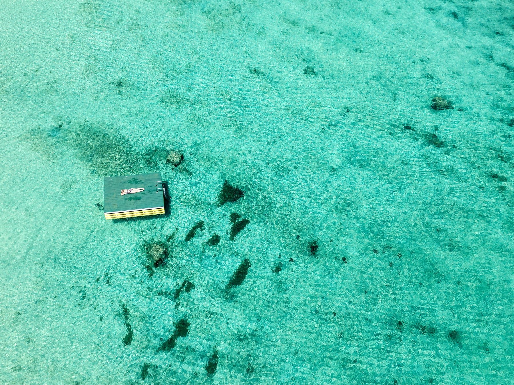 Woman lying on pontoon in crystal clear water on Norfolk Island